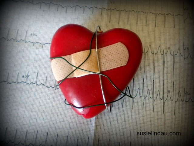 Red plastic heart with bandaid on top ECG chart
