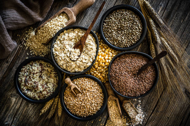 Large group of wholegrain food shot on rustic wooden table Top view of wholegrain and cereal composition shot on rustic wooden table. This type of food is rich of fiber and is ideal for dieting. The composition includes oat flakes, brown rice, dried corn,spelt, hemp seeds and flax seeds. Predominant color is brown. XXXL 42Mp studio photo taken with SONY A7rII and Zeiss Batis 40mm F2.0 CF fibre stock pictures, royalty-free photos & images