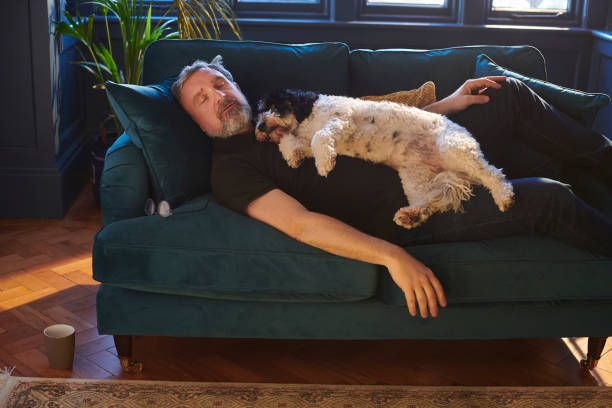 man and his small dog napping on the couch