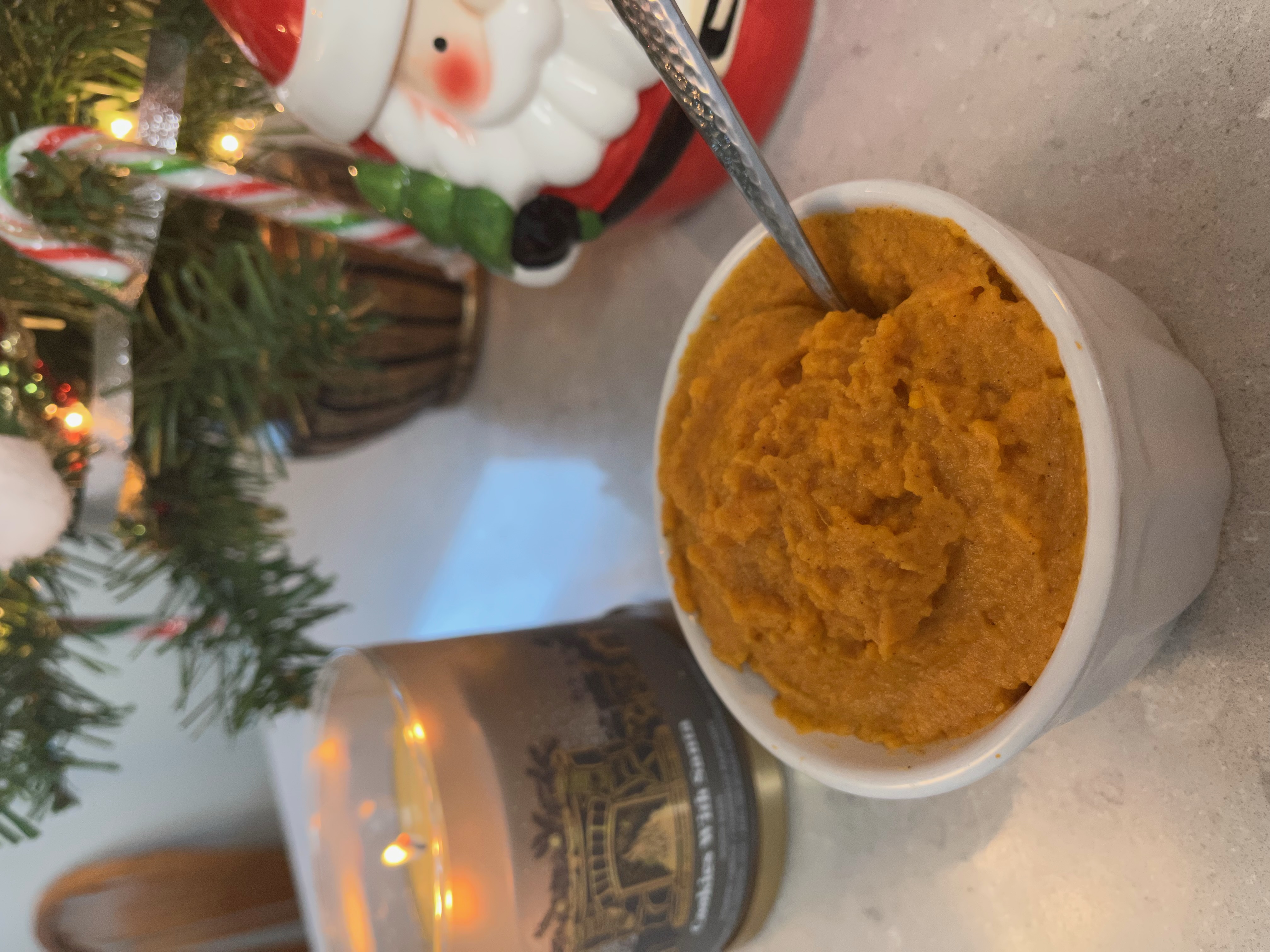 mashed sweet potatoes in a bowl in front of blurred Christmas background 