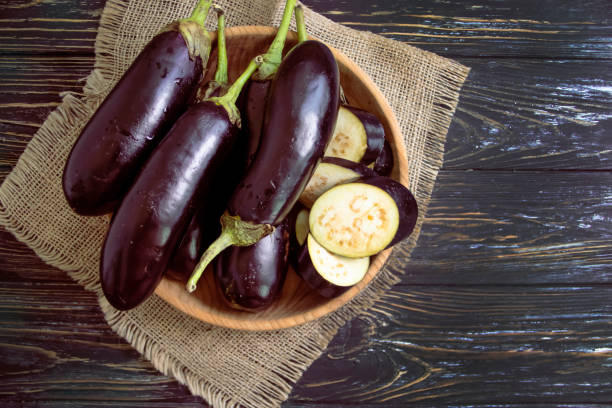 whole eggplant on wooden background whole eggplant on wooden background eggplant stock pictures, royalty-free photos & images