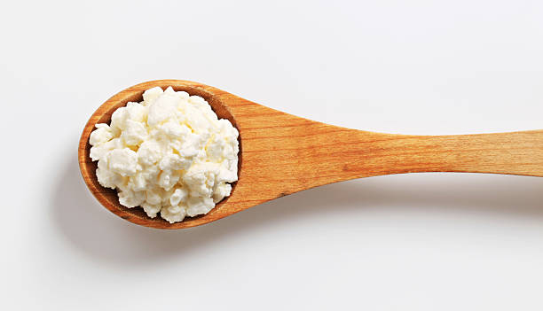 cottage cheese on a wooden spoon fresh cottage cheese on a deep wooden spoon cottage cheese stock pictures, royalty-free photos & images