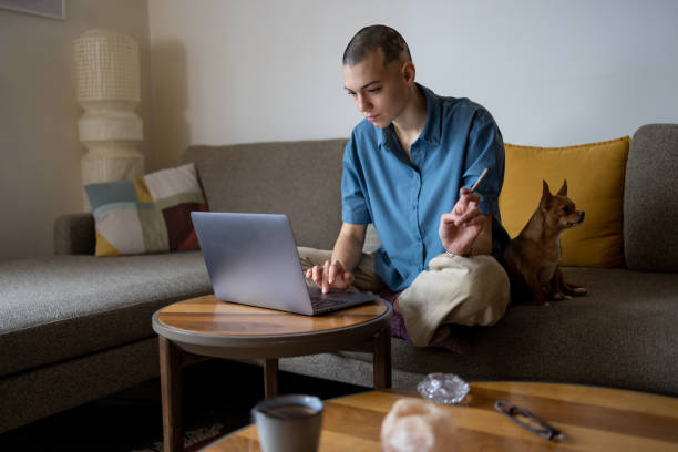 Young caucasian woman smoking CBD to relax with her pet Young caucasian female working from home on her laptop with CBD joint dog smoke stock pictures, royalty-free photos & images
