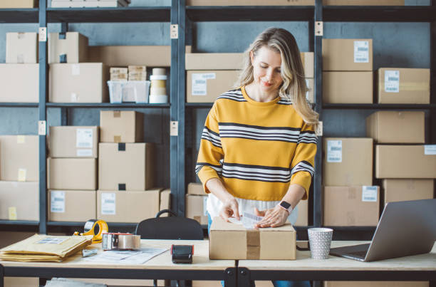 Mature woman running online store Mature woman at online shop. She is owner of small online shop. Receiving orders and packing boxes for delivery. shipmens stock pictures, royalty-free photos & images