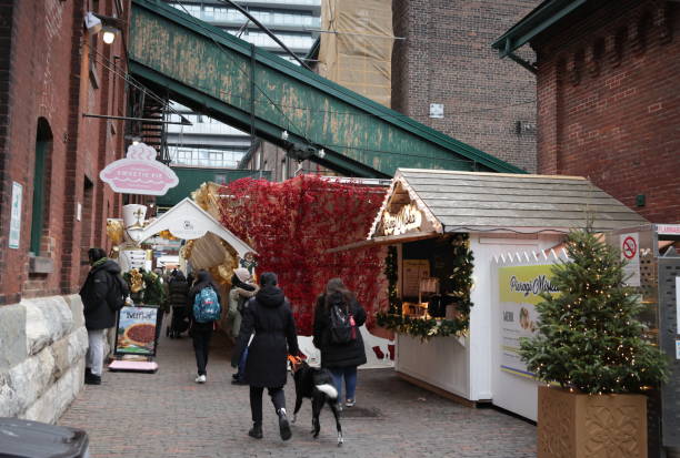 Toronto Christmas at The Distillery Historic District Toronto, Canada - December 7, 2022: Visitors and pets gather at The Distillery District Winter Village 2022 on Mill Street. Christmas market vendors sell from decorated stalls lining this pedestrian zone in the St. Lawrence neighbourhood. Gooderham and Worts Distillery National Historic Site. dog christmas market stock pictures, royalty-free photos & images