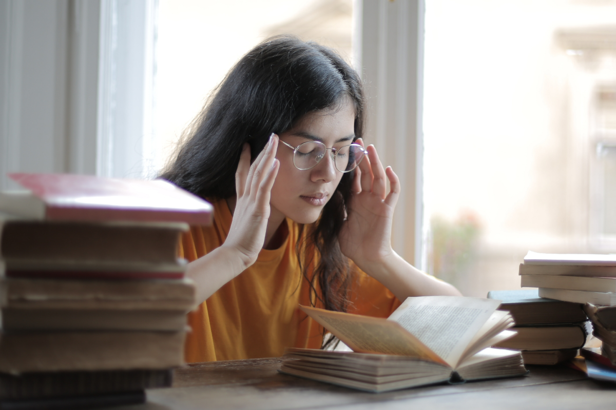 Woman with epilepsy and migraines rubbing her temples while reading