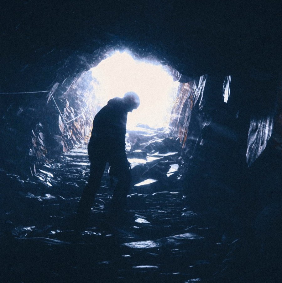 Una persona subiendo por una cueva hacia la luz.