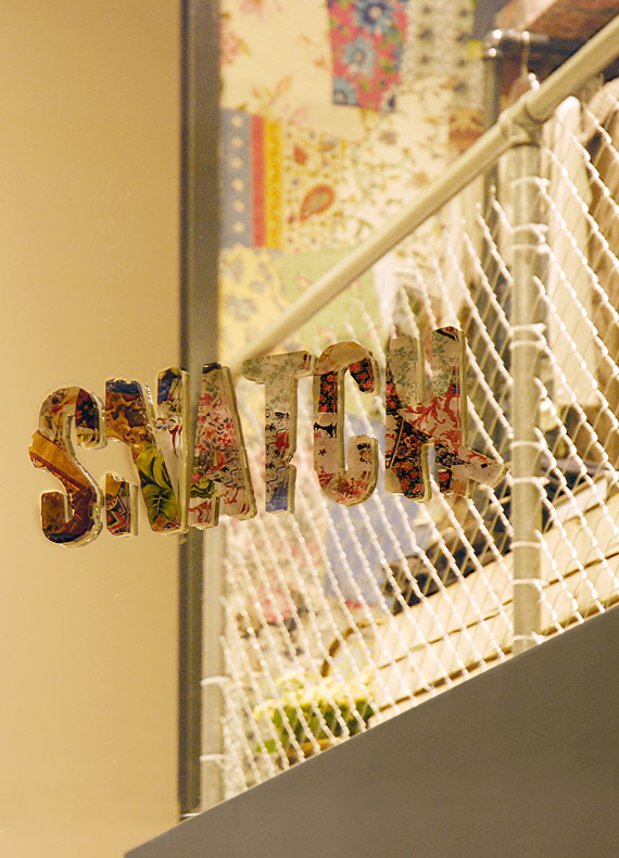 A retail shop sign with a vintage-style patchwork logo.