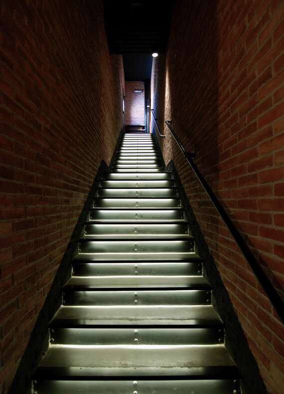 The stairway of an industrial restaurant bar which combines a sleek modern design with timeworn charm.