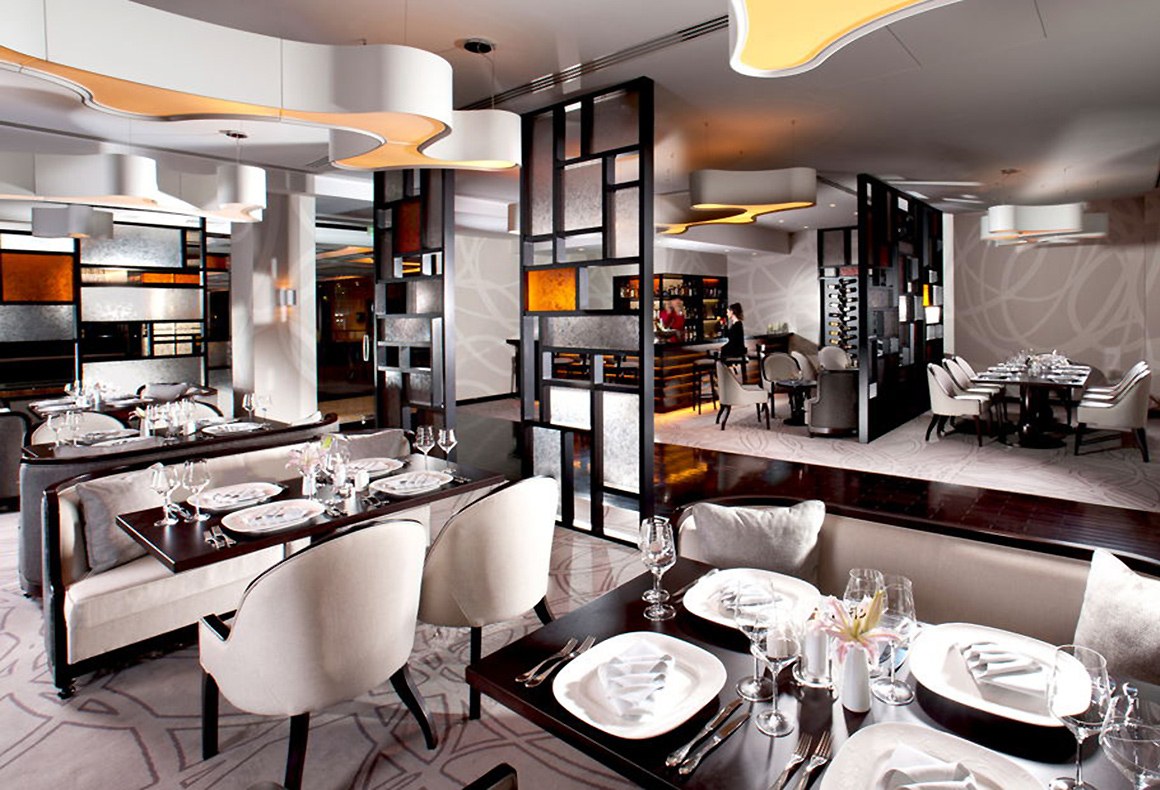 A restaurant design featuring a juxtaposition of geometric and organic forms in a neutral 2-tone scheme with orange accents.