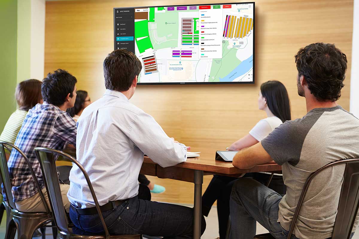 Event staff meeting reviewing Spot Campus admin panel on TV screen
