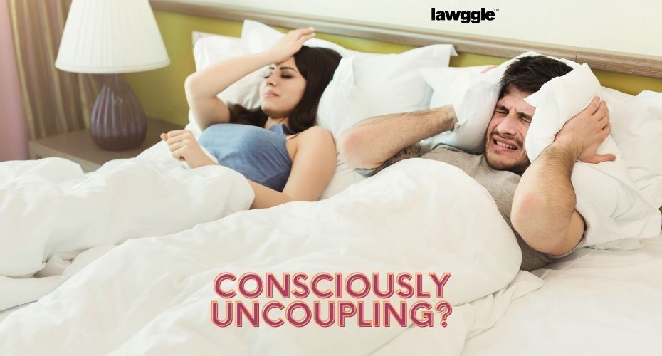 A couple lies in bed beside each other, each looking frustrated with the other.