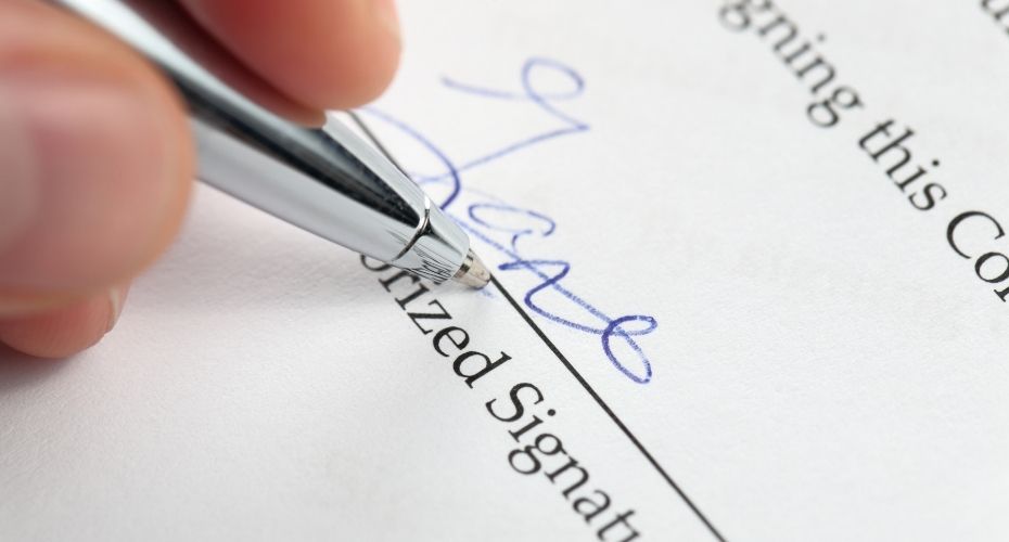 A silver pen signs the signature section of a Will.