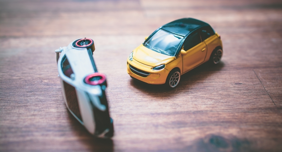 A toy car is flipped onto it's side after being crashed into by another toy car.