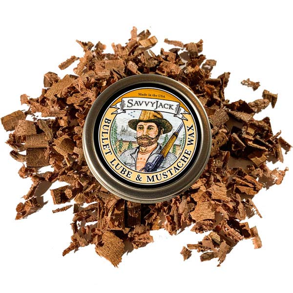 Strong hold SavvyJack mustache wax 1 oz tin. Front of mustache wax tin on wood chips.