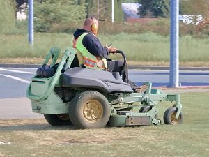 Landscaper looking at cell phone while riding a mower