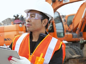 Construction Supervisor with Clipboard, Heavy Equipment in Background