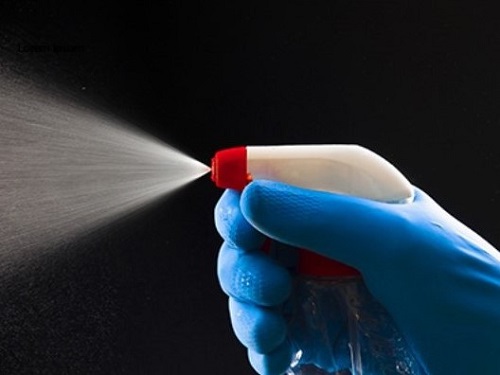 Gloved Hand Spraying Disinfectant Bottle