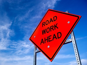 Road Work Ahead Hazard Sign Against Blue Sky