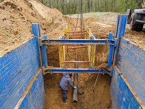 Worker Laying Pipe in Deep Trench