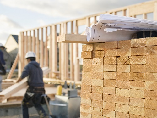 Construction Worker Carrying Lumber on Construction Site