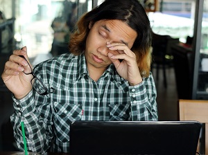 Person Rubbing Eyes After Working on Computer