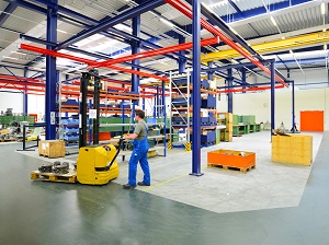 Warehouse with worker using a pallet jack while walking.