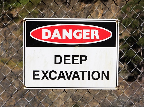 Sign on chain link fence that says Danger, Deep Excavation.
