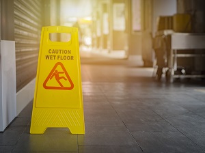 Foldable, yellow, caution wet floor sign visible in a facility.