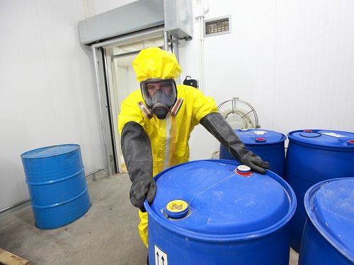 Worker wearing PPE, Hazardous Material Canisters in Storage
