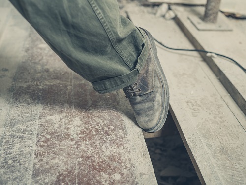 Construction worker's boot getting tripped into a floor hole on construction site.