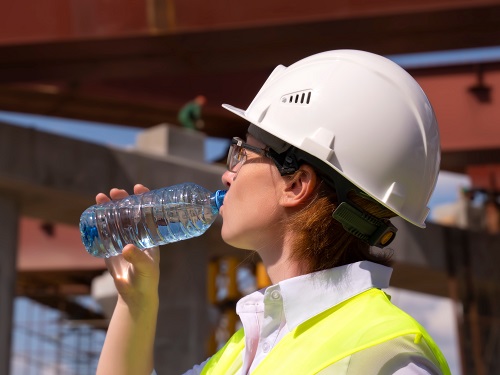 Outdoor construction worker drinking water from a water bottle.