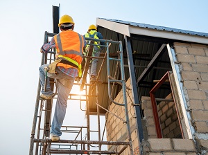 Worker climbing onto a supported scaffold from the side.