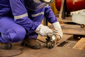 Construction worker wearing PPE and using an electrical tool.