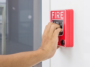 A worker pulling the fire alarm in the hallway of a building.