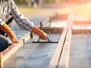 Worker wearing gloves smoothing out cement in forms.