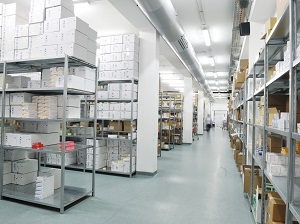 A clean and bright storage room that is in a corporate building with aisles that are kept clear.