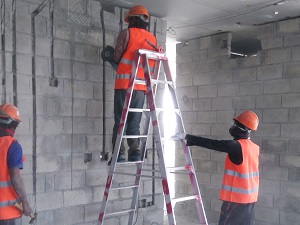 A worker standing backwards on a step ladder.