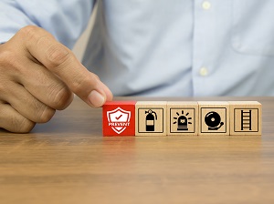 Person's hands touching some small wooden blocks with fire safety logos on them.