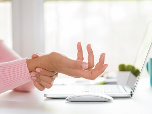 Office worker experiencing carpal tunnel pain in wrist.