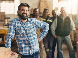 Small business owner in his workshop posing in front of his team.
