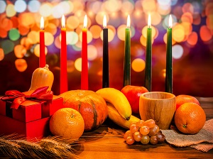 A Kwanzaa kinara with fruits placed in front of it.