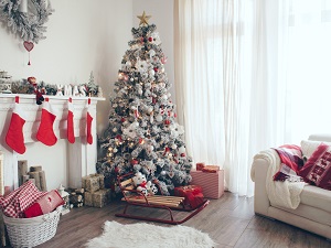 A Christmas scene inside with a tree, stockings on a fireplace, and presents.