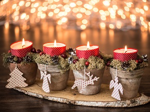 Four candles decorated with festive holiday ornaments.
