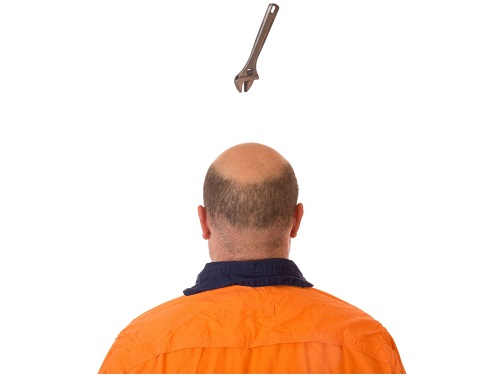 Re-enactment of a worker who is not wearing a hard hat with a tool about to hit his head.