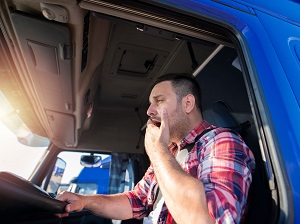 A truck driver yawning while driving.