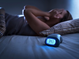 A person laying in bed unable to sleep at night.