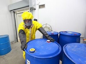 Worker wearing PPE, Hazardous Material Canisters in Storage