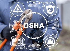 A worker holding tools and wearing gloves standing behind a sign that says OSHA.
