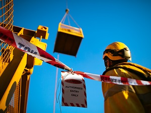A worker is watching a load being lifted by a crane.